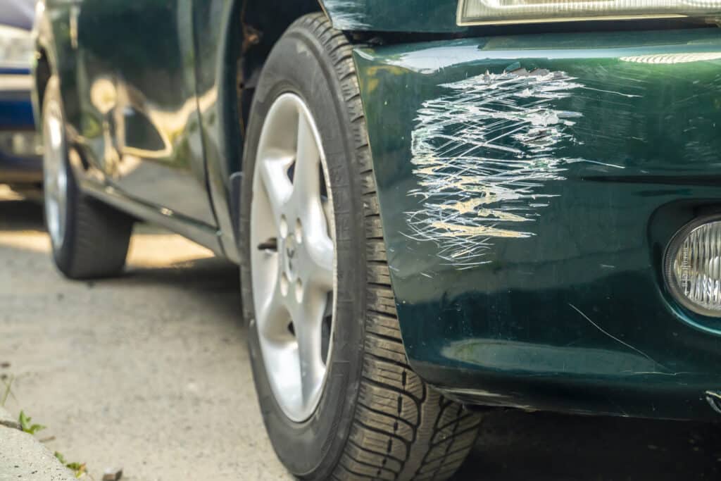 Green scratched car with damaged paint in crash accident.