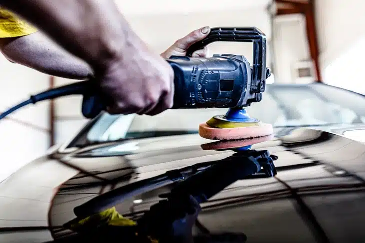 Professional Car Mechanic is Using Polishing Machine to Clean the Car bonnet in Auto Service.