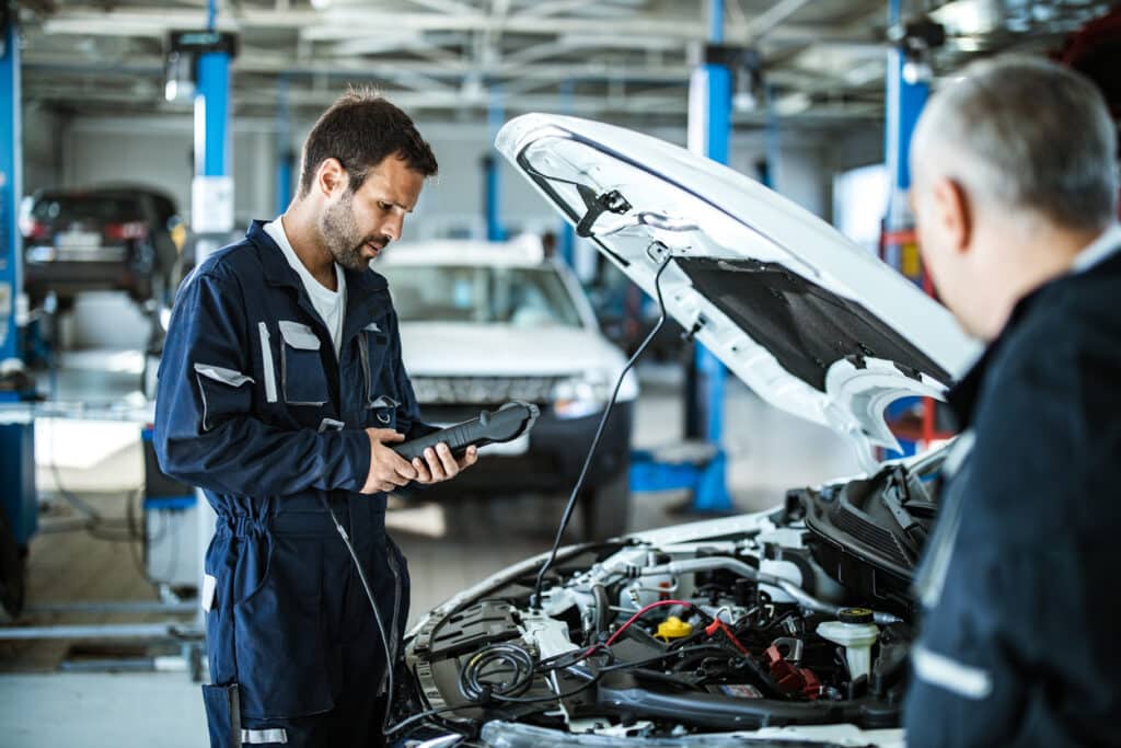 young mechanic analyzing car's performance with diagnostic tool in a workshop.