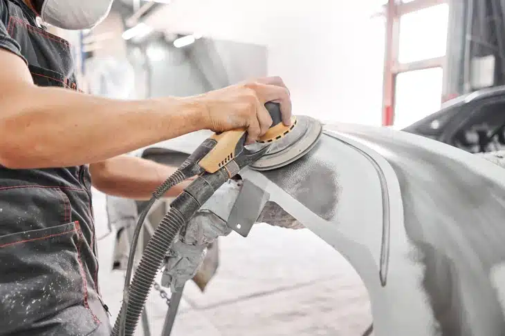 Grey car parts being sanded down by a grinding tool