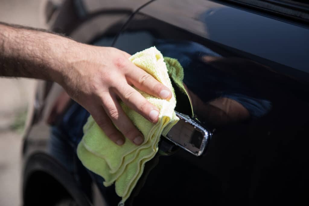 a man wipes a wet car with a rag