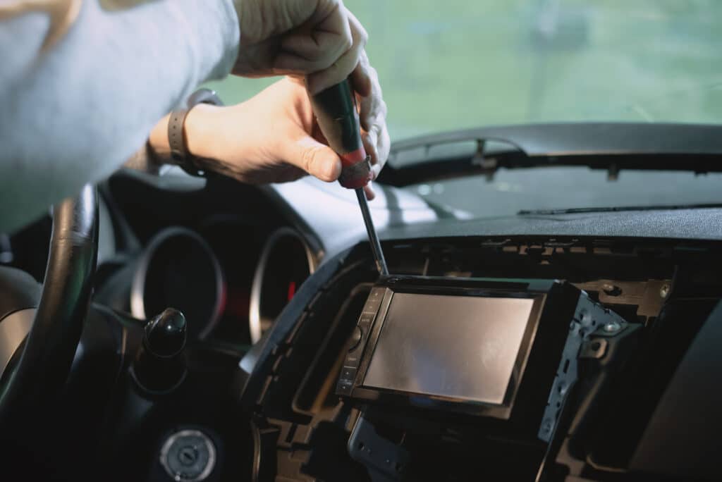 Auto electrician is installing a car radio sound system close up.